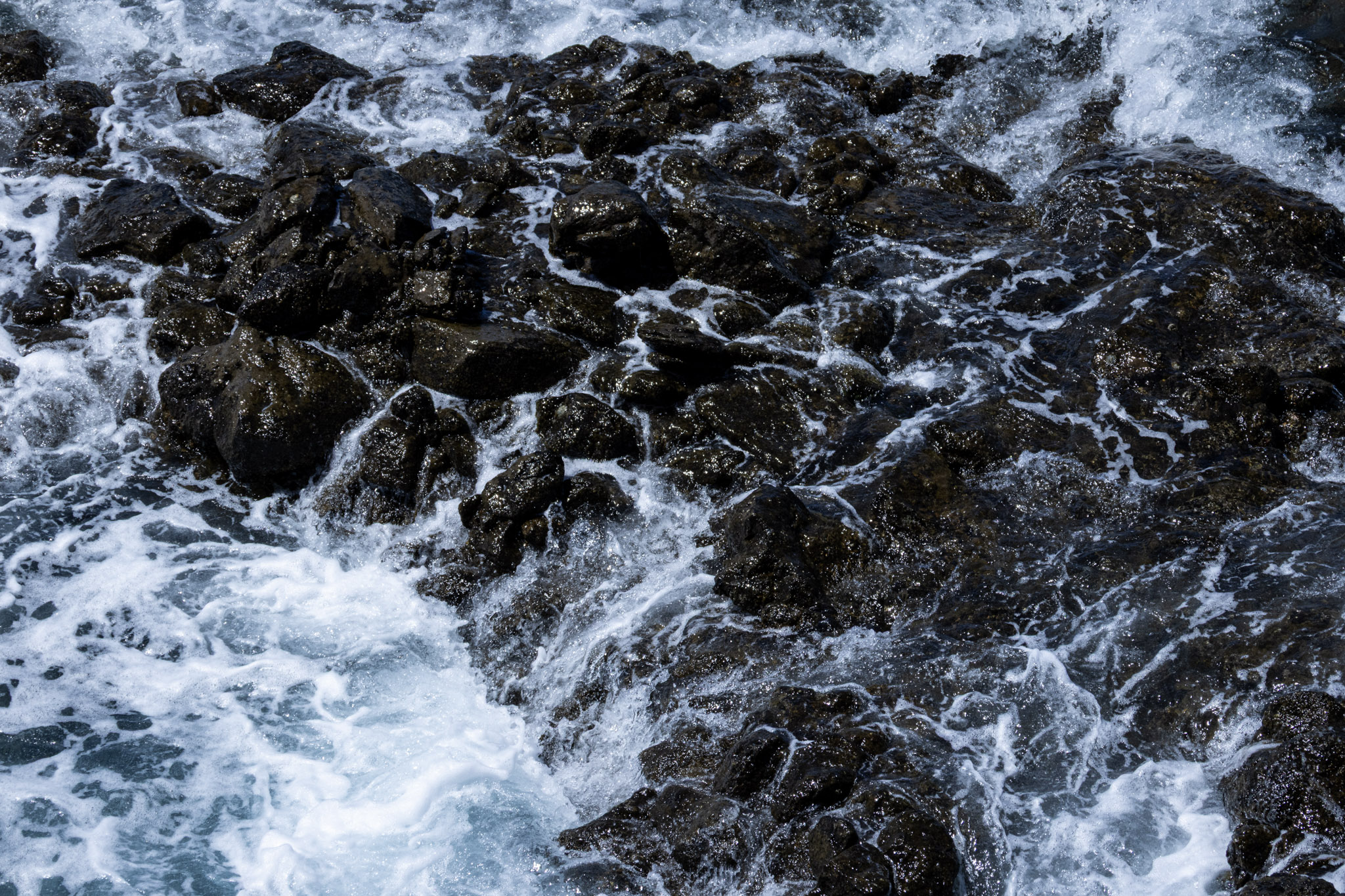 White water flowing around dark coastal rocks